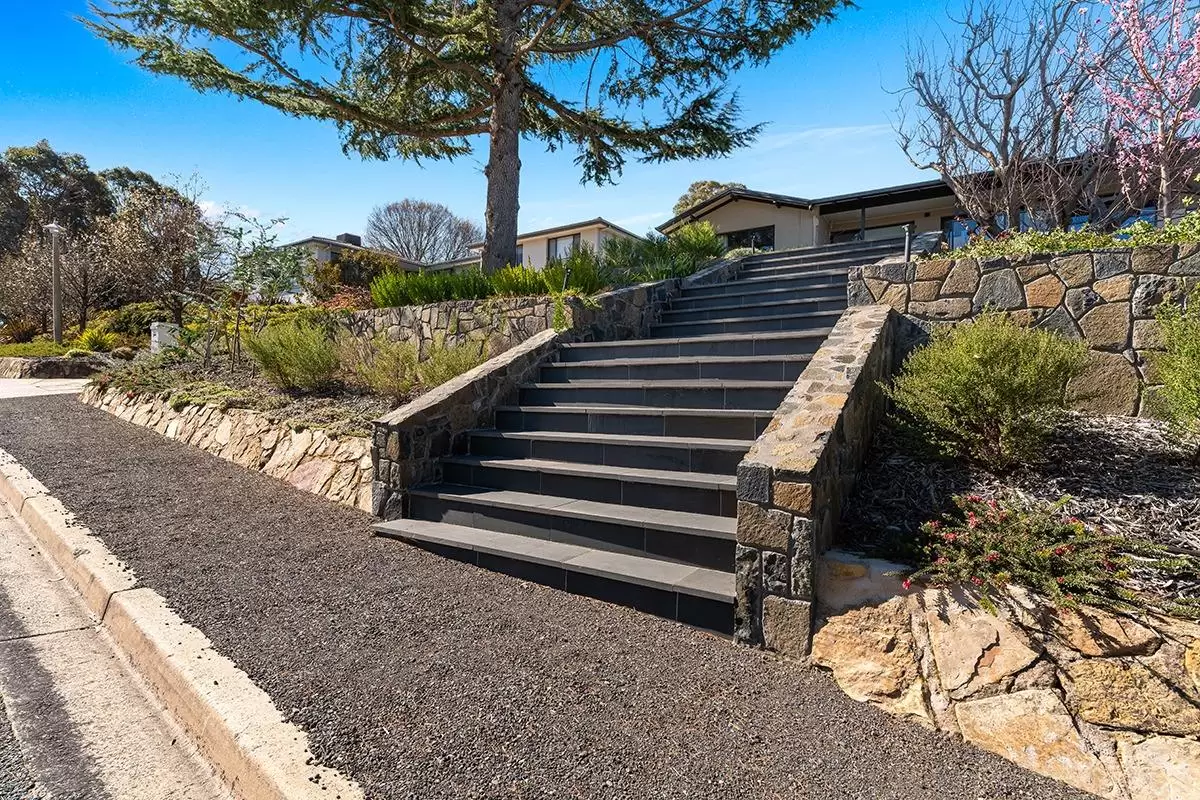Wide stone staircase with stone retaining walls beside a gravel path