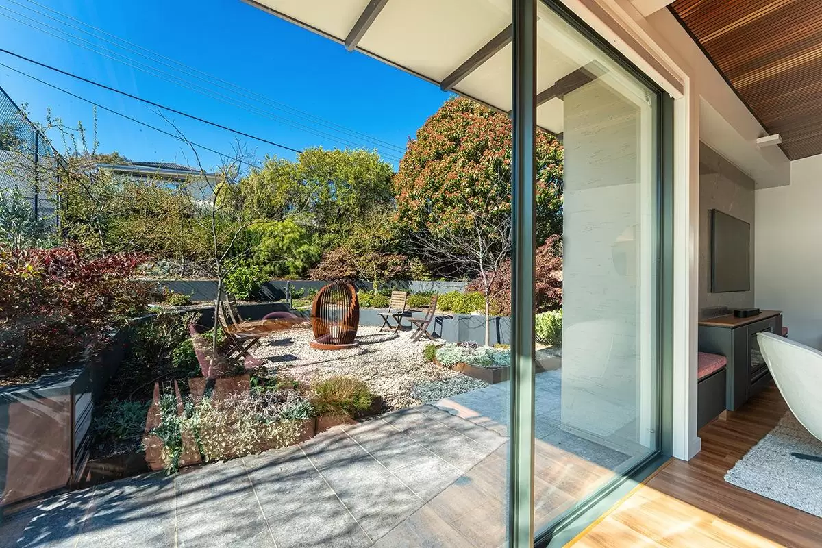 Garden courtyard with gravel, planting and a steel feature seen from the open sliding doors