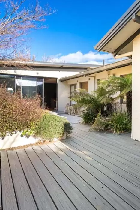 Grey decking walkway leading past a glass door to the home's courtyard entry
